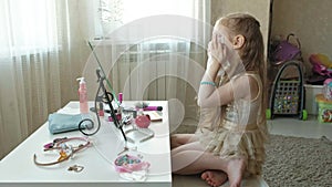 Little girl with red hair looks in the mirror, cleans the skin of the face with wet wipes, make-up, face, fashion, style