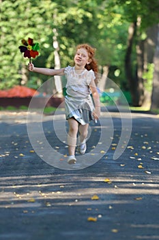 Little girl with red hair runs with windmill