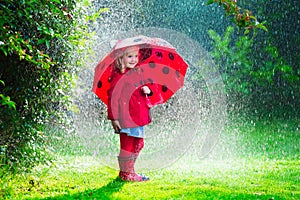 Little girl in red jacket playing in autumn rain