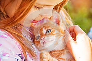 Little girl with a red kitten in hands close up. Bestfriends. I