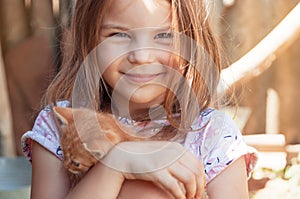 Little girl with a red kitten in hands close up. Bestfriends. I photo