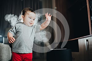 A little girl in red pants looks and touches the humidifier. Moisture in the house concept photo