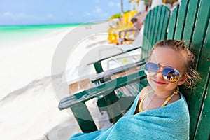 Little girl relaxing in colorful chair at beach