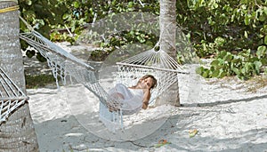 Little girl relaxing at cozy hammock in tropical garden