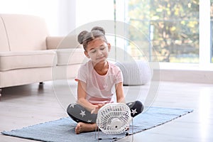 Little girl relaxing in front of fan at home