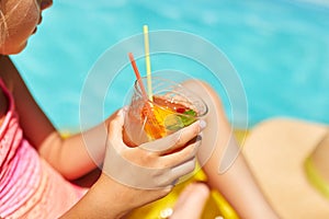 Little girl relaxing in swimming pool, enjoying suntans, drink a juice on inflatable yellow mattress