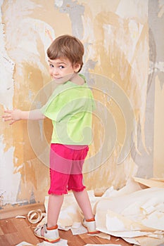 Little girl remove old wallpapers from wall