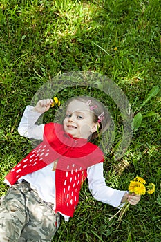 Little girl resting on green grass outdoors in spring park