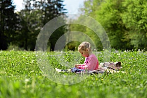 Little girl resting on a green meadow among meadow flowers