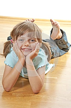 Little girl resting on a wooden floor