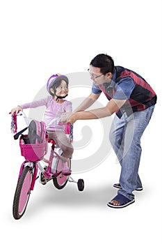 Little girl ride bicycle with dad in studio