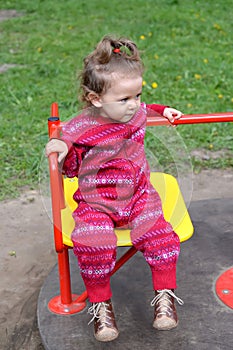 The little girl rides a roundabout. Playground