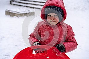 A little girl rides a sled from a winter slide