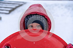 A little girl rides a sled from a winter slide