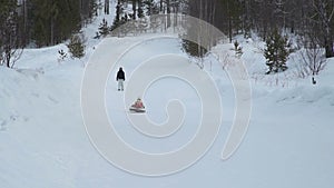 Little girl rides on a sledding tubing from hill