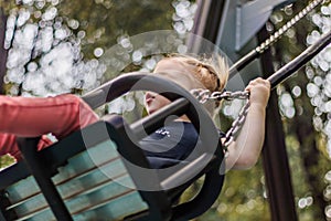 Little girl rides on a swing in the park