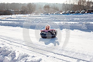 A little girl rides a tubing down a slide