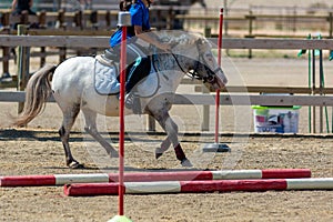 Little girl that rides a white pony during Pony Game competition at the Equestrian School