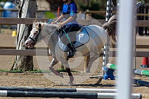 Little girl that rides a white pony during Pony Game competition at the Equestrian School