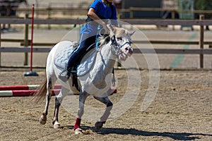 Little girl that rides a white pony during Pony Game competition at the Equestrian School