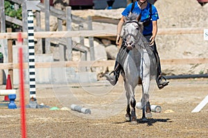 Little girl that rides a white pony during Pony Game competition at the Equestrian School