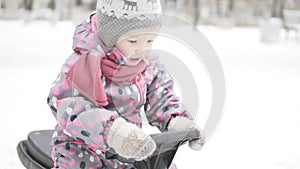 Little girl rides in the winter on a snow scooter