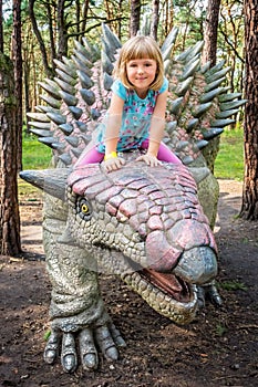 Little girl riding on Ankylosaurus dinosaur