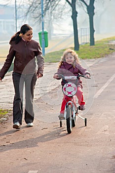 Little girl riding a bike, bycicle with mother