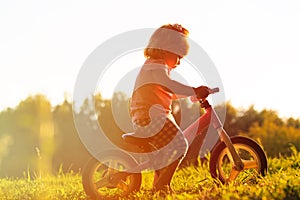 Little girl riding bike at sunset, active kids