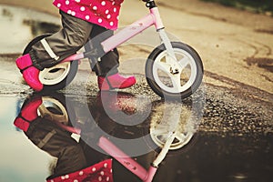 Little girl riding bike in water puddle