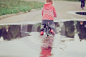 Little girl riding bike in water puddle