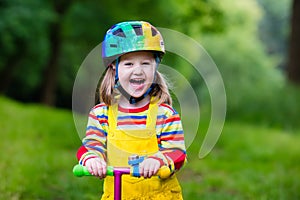 Little girl riding a colorful scooter