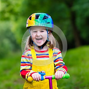 Little girl riding a colorful scooter