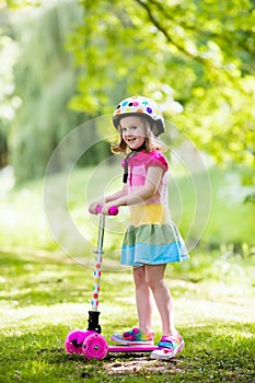 Little girl riding a colorful scooter