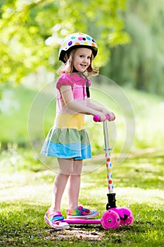 Little girl riding a colorful scooter