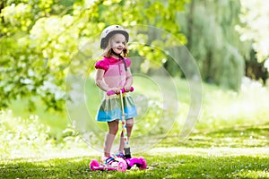 Little girl riding a colorful scooter