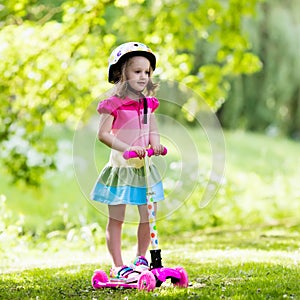 Little girl riding a colorful scooter