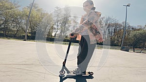 little girl riding and doing tricks by Kick Scooter in extreme Park
