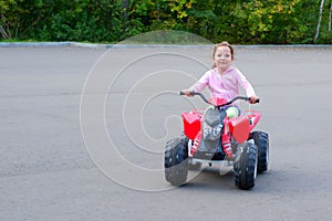 Little girl is riding on a electric quadricycle. Children`s summer vacation and entertainments
