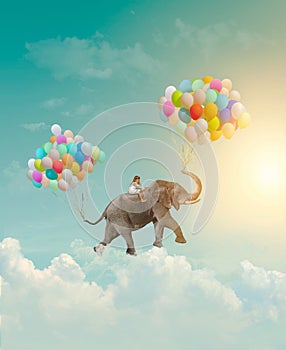 Little girl riding an elephant with balloons, flying in the sky; fantasy, metaphor, achievement concept