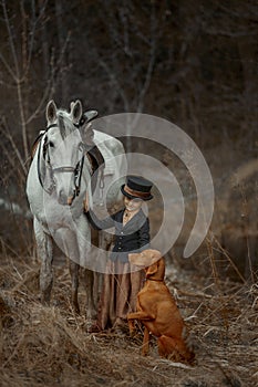 Little girl in riding habit with horse and vizsla