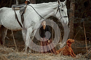 Little girl in riding habit with horse and vizsla