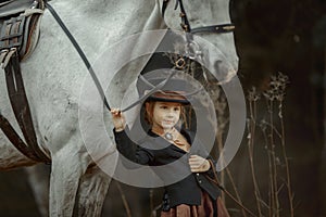 Little girl in riding habit with horse and vizsla