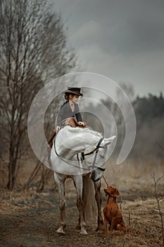 Little girl in riding habit with horse and vizsla