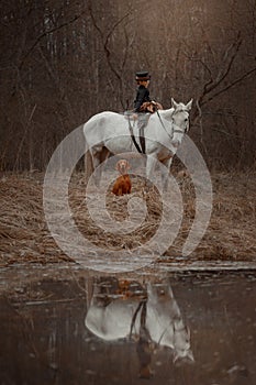 Little girl in riding habit with horse and vizsla