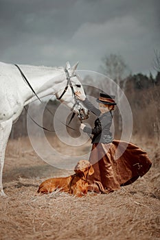 Little girl in riding habit with horse and vizsla