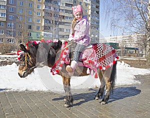 Little girl riding her pony on photo