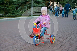 Little girl is riding in a park on a tricycle