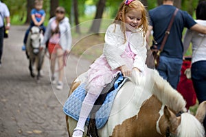 Little girl riding on a pony in a city park