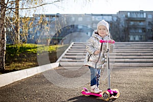 Little girl riding a scooter in the Park on a Sunny spring day. Active leisure and outdoor sport for children